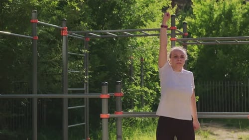 Woman Performing a Warmup Stretch Routine in an Outdoor Setting The Exercise Takes Place on a Sunny