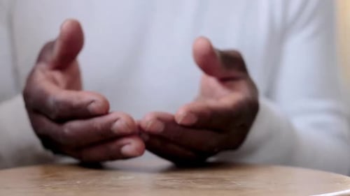 Mann betet mit zusammengefügten Händen zu Gott, karibischer Mann betet mit weißem Hintergrund, Stock-Bildmaterial