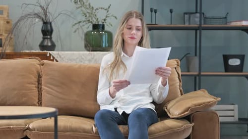 Upset Young Woman Shocked while Reading Documents at home
