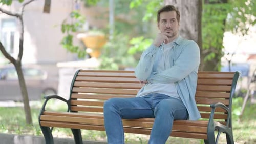 Man Thinking on Park Bench on a Sunny Day