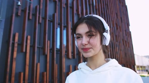 Woman Listens to Music on Phone in City