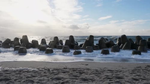 Slow motion panning shot of the tetrapods protecting the shore from the waves at the beach of Hörnum