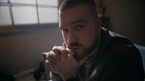 Thoughtful Man Sitting with Hands Clasped Looking at Camera
