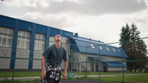 Athlete Throws Up Volleyball and Slams It on Basketball Court with Blue Building Background