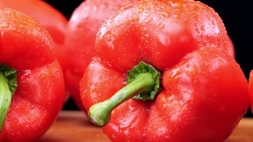 Fresh red peppers on wooden chopping board, extreme close-up