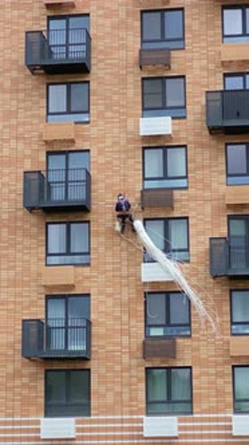 An industrial climber insulates the facade of a residential building with insulation