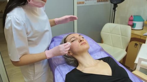 Cosmetic Facial Cleansing Procedure in Beauty Clinic with Woman Client Lying on Treatment Bed