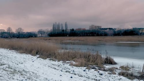panoramic snowed landscape around frozen lake trees and town buildings at back