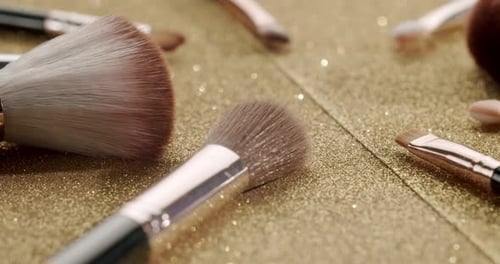 Professional Cosmetic Makeup Brushes Set on Gold Glitter Background