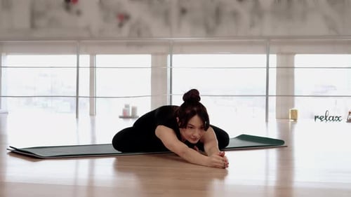 Woman Practicing Yoga and Stretching Fitness at Gym Studio with Window Background