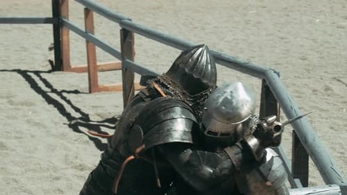 Slow motion tracking shot of two knights fighting mutual on sandy field.Close up shot.