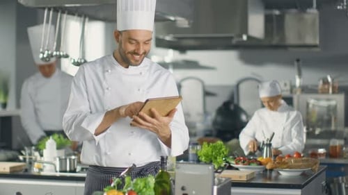 Famous Chef Uses Tablet Computer for Recipes While Working in a Modern Kitchen.