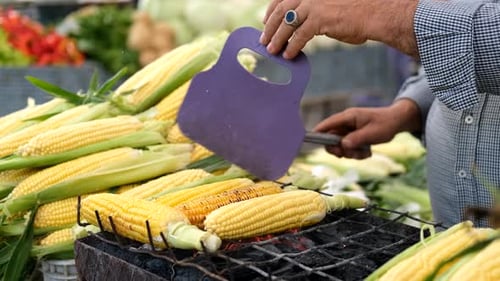 Nahaufnahme eines Mannes, der Mais auf dem Grill zubereitet
