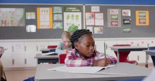 In School Girl Writing In Notebook At Desk Focus on her work