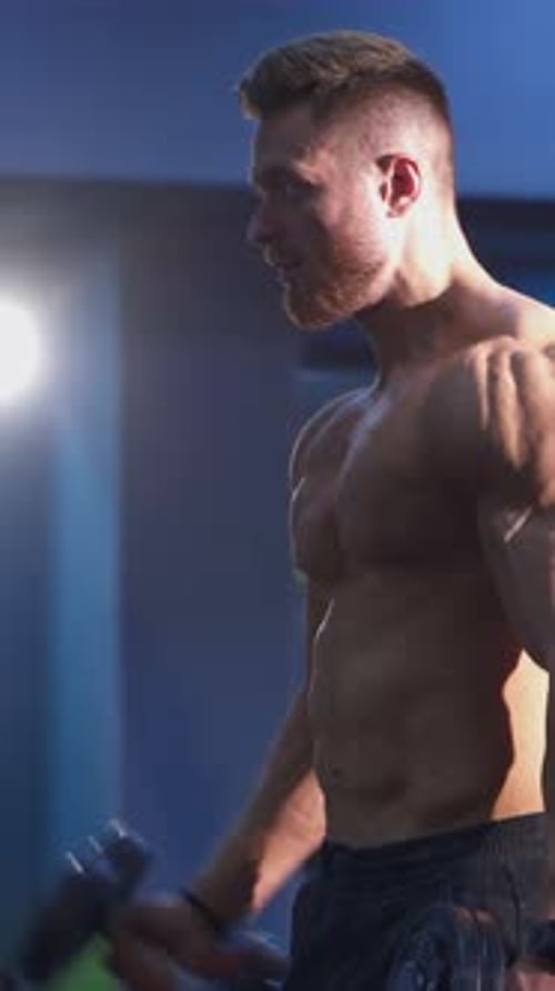 Muscular Man Working Out Biceps with Dumbbells