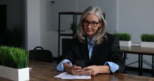 Successful Caucasian Middle Aged Older Businesswoman Leader Sits at a Desk in the Office and Types