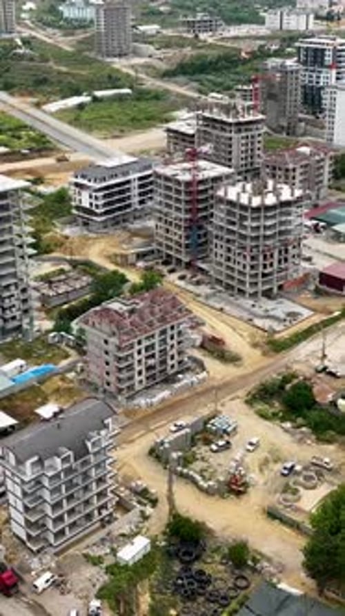 Vídeo vertical: descripción aérea de un centro comercial: constructores de construcción que gestionan la logística de vigas metálicas
