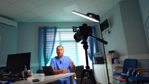 Confident male doctor in blue uniform recording a video for his vlog.
