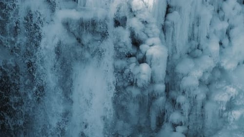 Nahaufnahme von Wasser, das im Winter auf eine eisige Klippe fällt. Gefrorene Wasserfalllandschaft