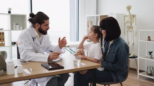 Caucasian Doctor Checking Young Girl's Temperature in Clinic Setting