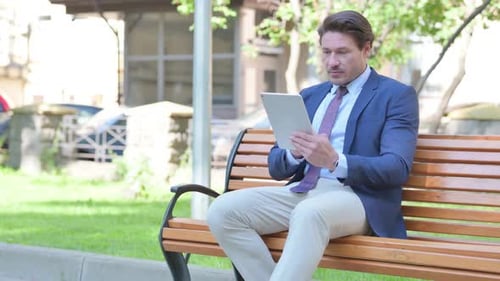 Man Reacting to Tablet News While Sitting