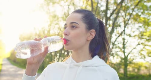 Close Up Portrait of Caucasian Young Beautiful Female Standing Outdoors Drinking Water From Bottle