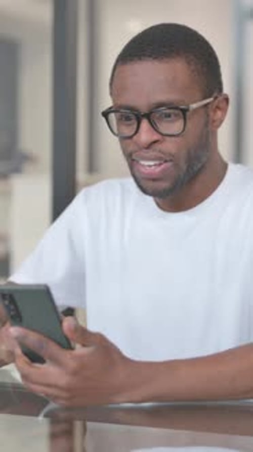 Young Man Cheers While Looking at His Phone