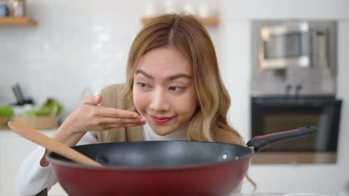 Woman Cooking and Enjoying Food in a Kitchen