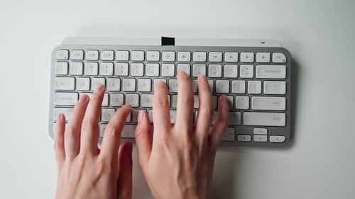Nahaufnahme einer modernen Büroangestellten in blauem Hemd, die direkt an einem Tisch sitzt und direkt tippt