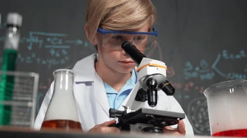 Boy in Lab Coat Using Microscope in Classroom