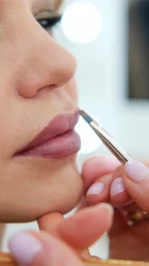 Close Up Professional Lips Makeup Beautician Applies Lipstick Beautiful Woman Face Hand of Makeup