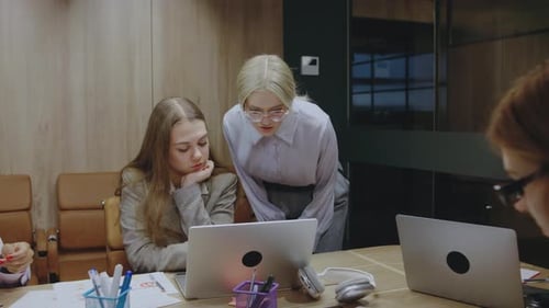 A Productive Meeting in a Modern Office Where Young Professionals Collaborate Over Laptops