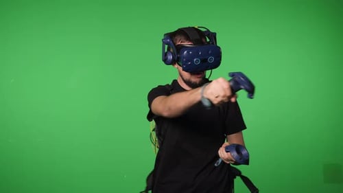 A Man Uses Virtual Reality Glasses to Play in a Studio on a Green Background