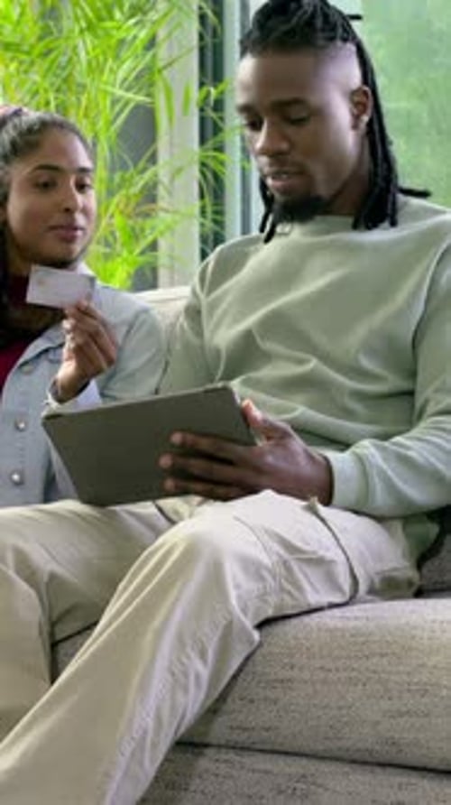 Vidéo verticale : montrant une femme tenant une carte, un homme tapant sur une tablette, célébrant un achat dans le salon