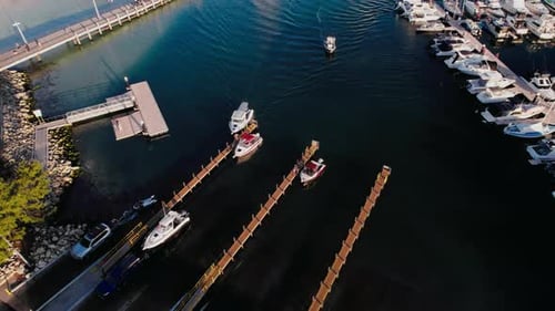 Boats maneuvering through a tranquil marina at sunset with docked vessels and calm waters