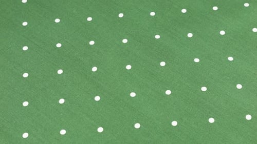 Top view of the viridian green with white polka dots cotton fabric rotated on the display case.
