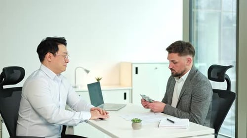 Businessmen Discussing a Contract and Counting Money in a Modern Office
