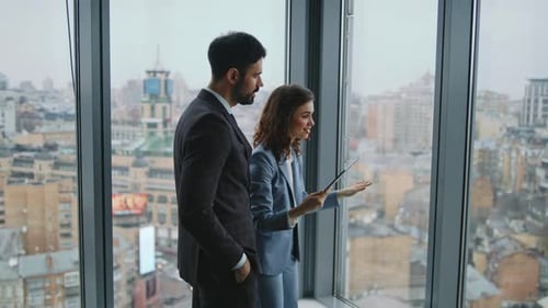 Couple Coworkers Talking Standing at Office Window Colleagues Discussing Work