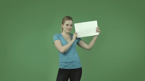 caucasian casual blond girl isolated on green happy with blank sign