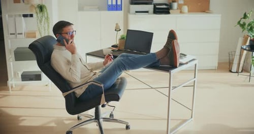 Man Talking on Phone with Feet on Desk