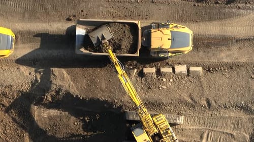 Excavator Filling Dump Truck at Construction Site