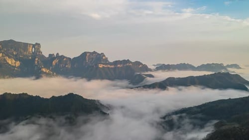Time-lapse stunning golden hour light sunrise with flowing clouds among mountains by forest morning