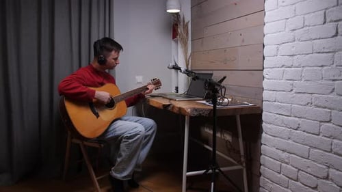 Young Man Playing Guitar in Home Music Studio