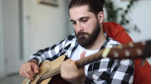 Adult plays guitar at home