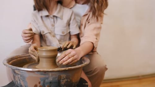 Mother and Daughter Making Pottery Together at Wheel