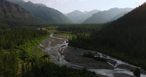 Aerial Shot of Sunlit River and Valley Surrounded by Mountains