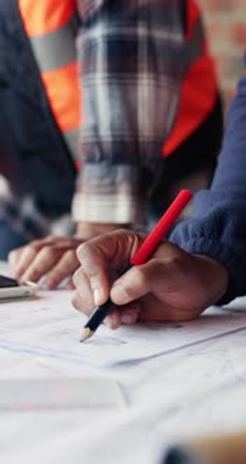 Discusión sobre la construcción, las manos y el equipo con un plano para el diseño de edificios