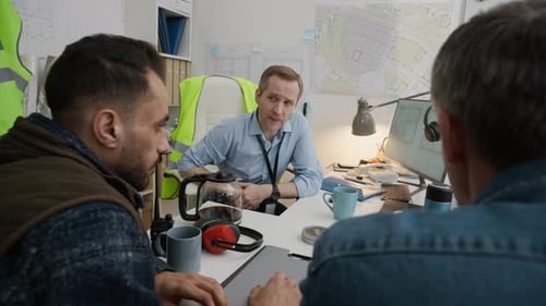 Multiethnic Civil Engineers Discussing Blueprints and Plans in Office