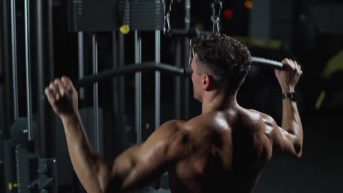 Night Time Athletic Man in the Gym Lifting Blocks on Gym Machine Training on Block Device and Gym