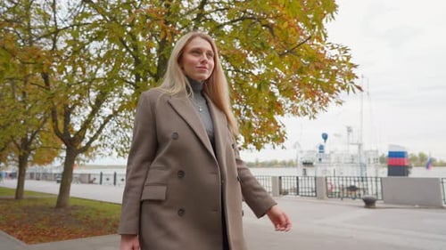 Attractive Business Woman with Blond Hair Walks in Autumn Park on Cloudy Day